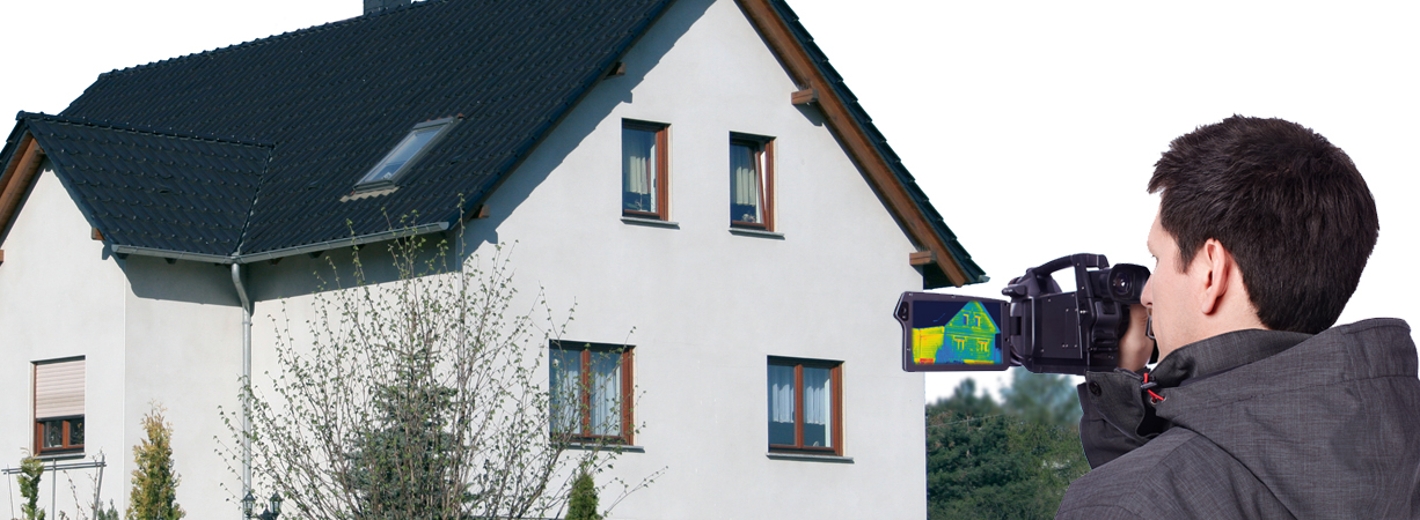 Mann mit Wärmebildkamera vor einem Haus