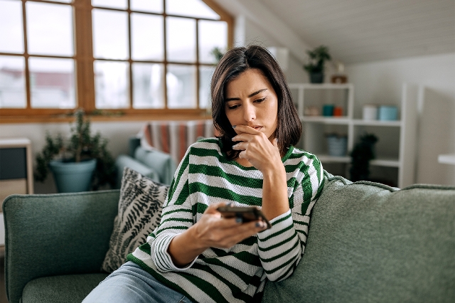 Frau mit Handy am Sofa