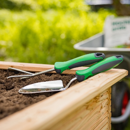 Gartenhandwerkzeug liegt am Rand eines Hochbeetes