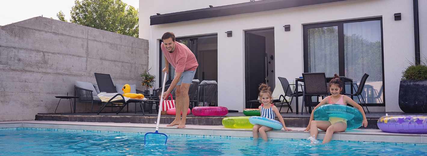 Mann reinigt Pool mit Kescher für zwei Mädels