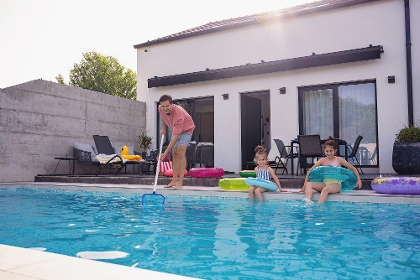 Mann reinigt Pool mit Kescher für zwei Mädels