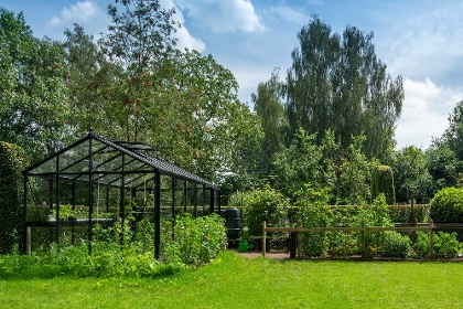 Schwarzes Gewächshaus im grünen Garten