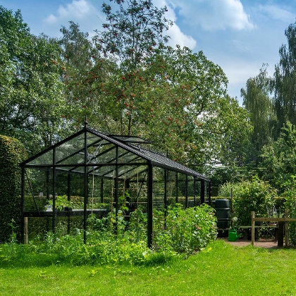 Schwarzes Gewächshaus im grünen Garten