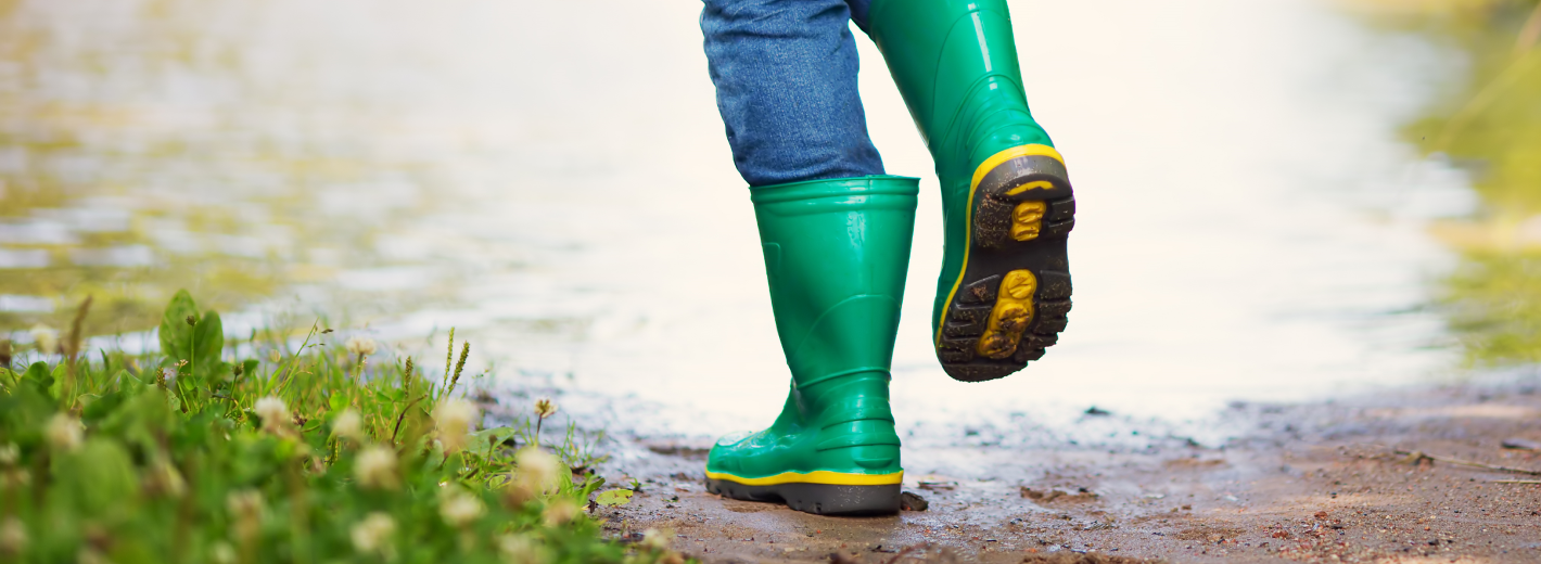 Mit Regenschirm und Gummistiefel im Regen gehen
