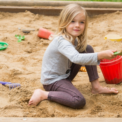 Mädchen spielt im Sandkasten mit Eimer und Schaufel