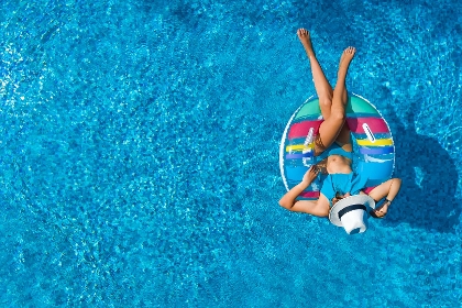 Aus der Vogelperspektive: Frau liegt auf Schwimmring im Pool