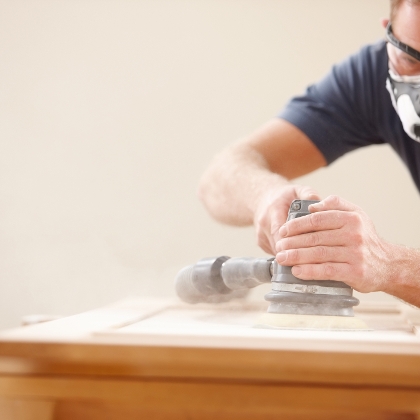 Handwerker schleift mit Schutzbrille und Schutzmaske
